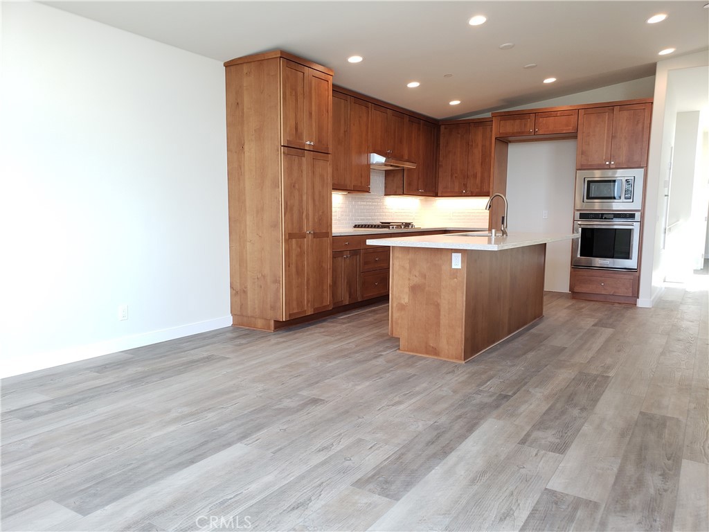 a large kitchen with stainless steel appliances kitchen island a large counter top and a wooden floors