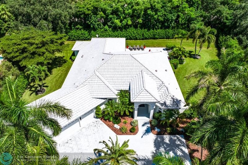 an aerial view of a house with a yard and trees all around