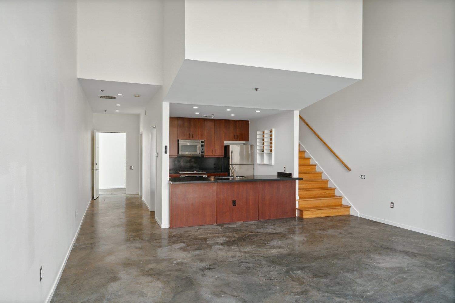 Kitchen with backsplash, a towering ceiling, appliances with stainless steel finishes, sink, and kitchen peninsula