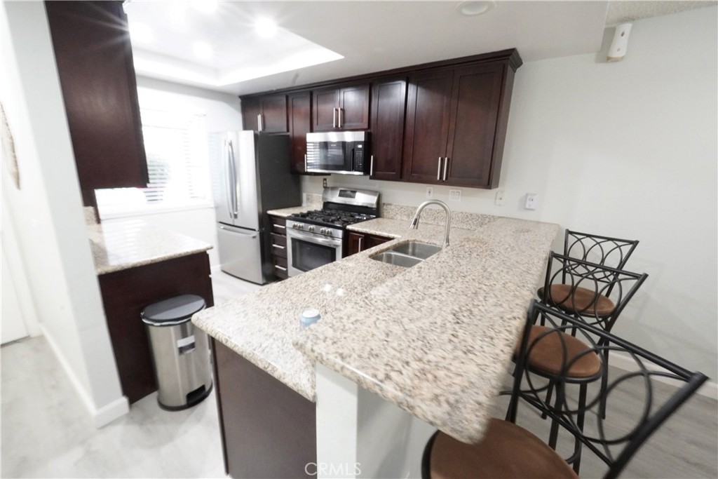 a kitchen with stainless steel appliances kitchen island granite countertop a table chairs in it and wooden floors