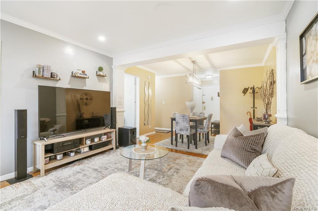 Living room with crown molding, decorative columns, and hardwood / wood-style flooring