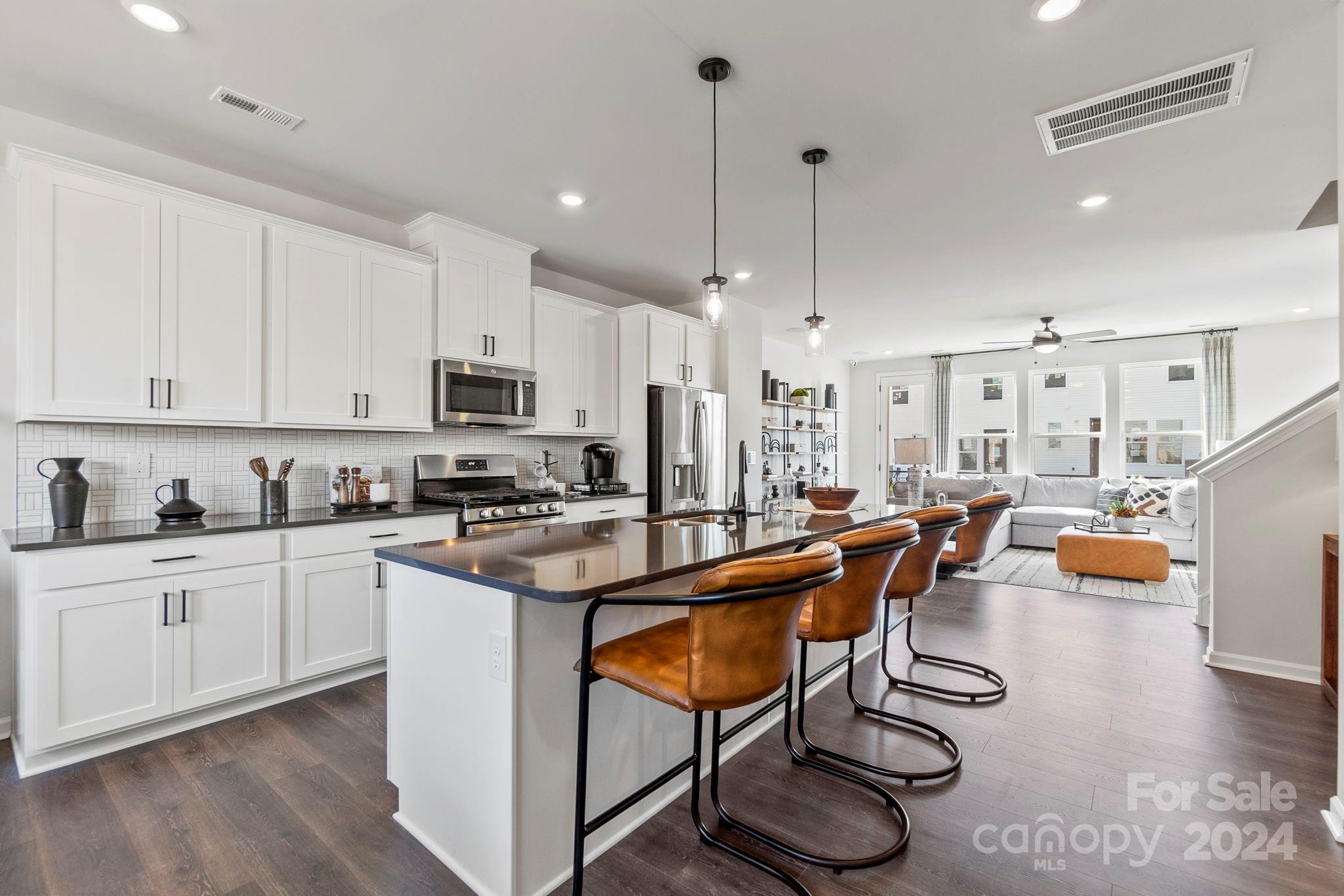 a kitchen with stainless steel appliances granite countertop a sink a stove and a wooden floors