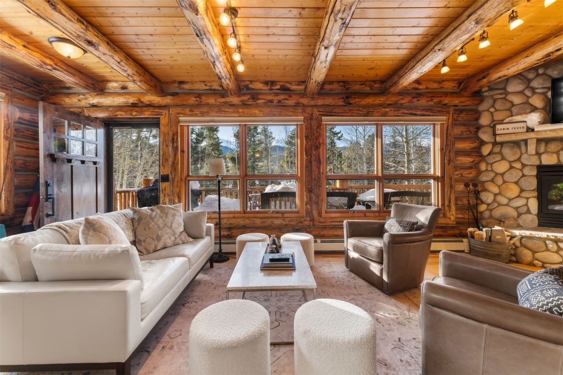 Living room featuring log beam ceiling, rustic walls, wooden ceiling