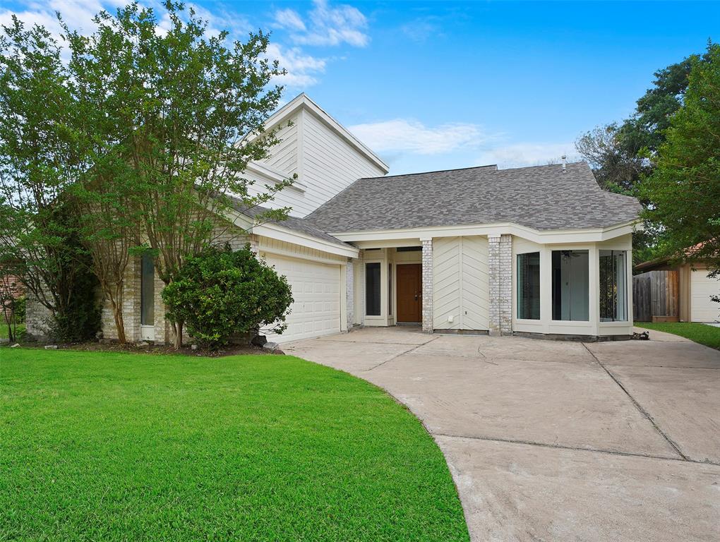 This is a single-story home featuring a two-car garage, a large front yard, and a bay window. The exterior includes a combination of brick and siding.