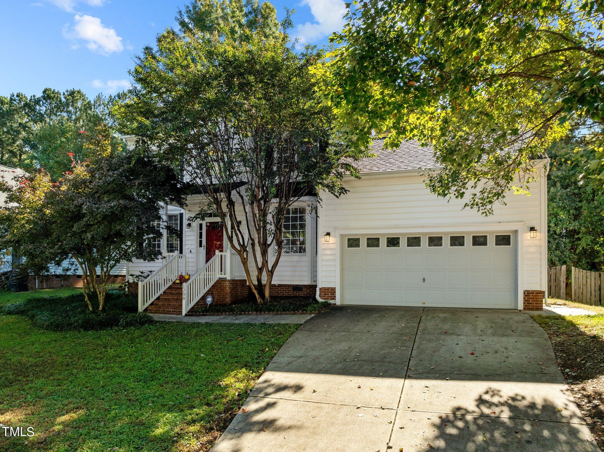 a view of a house with a yard and a large tree