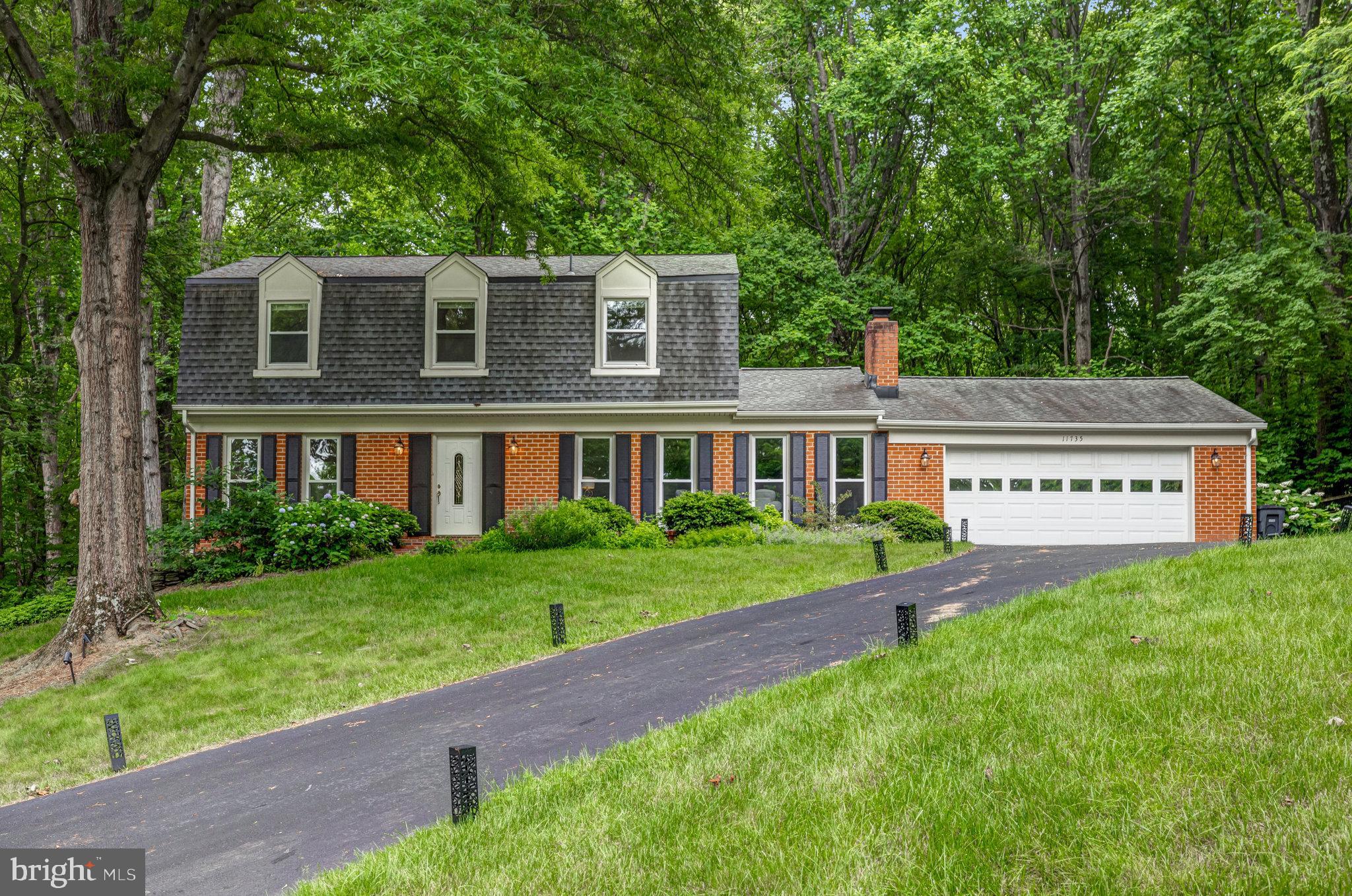 a front view of a house with a yard and trees