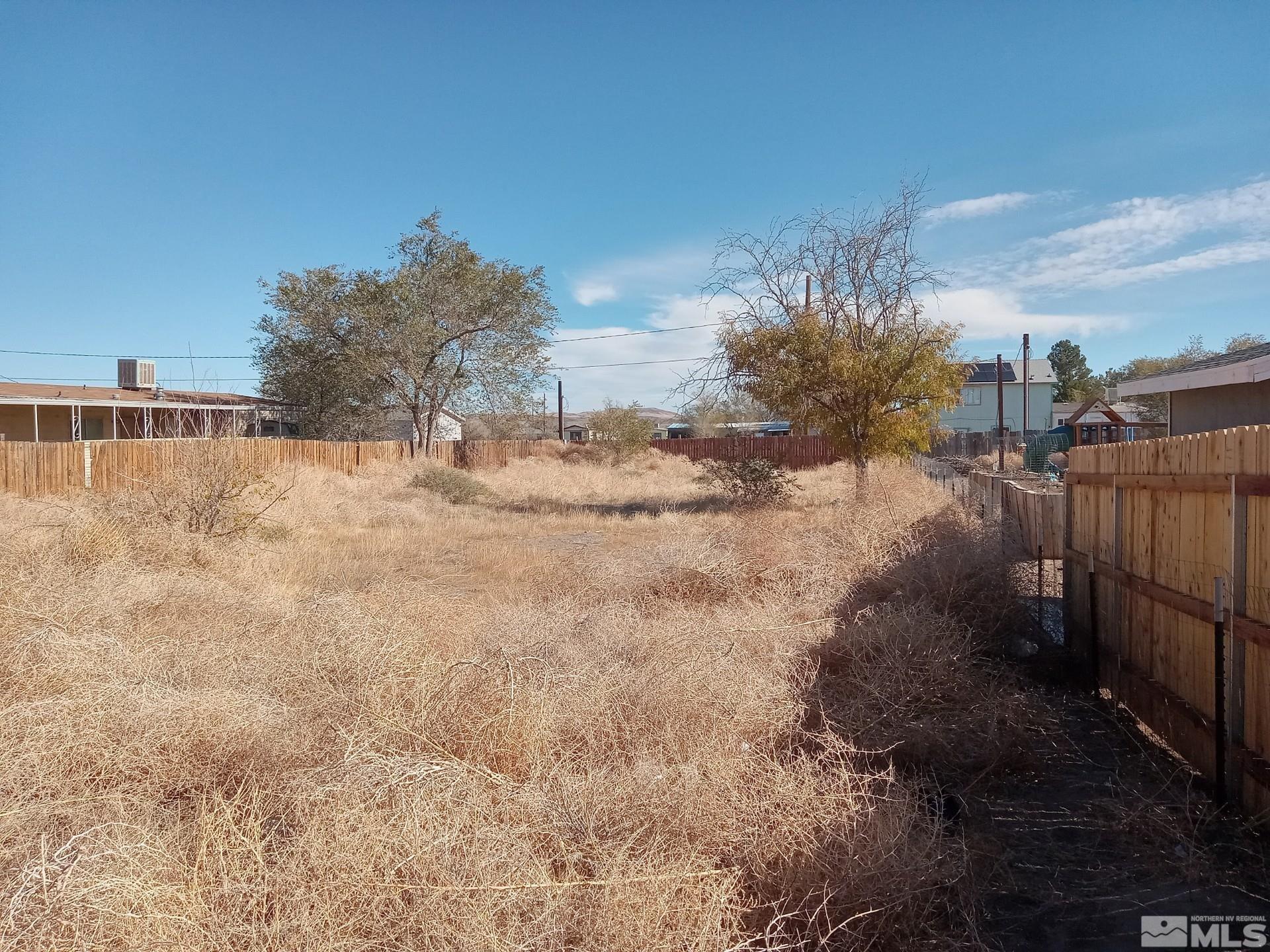 a view of a yard with wooden fence