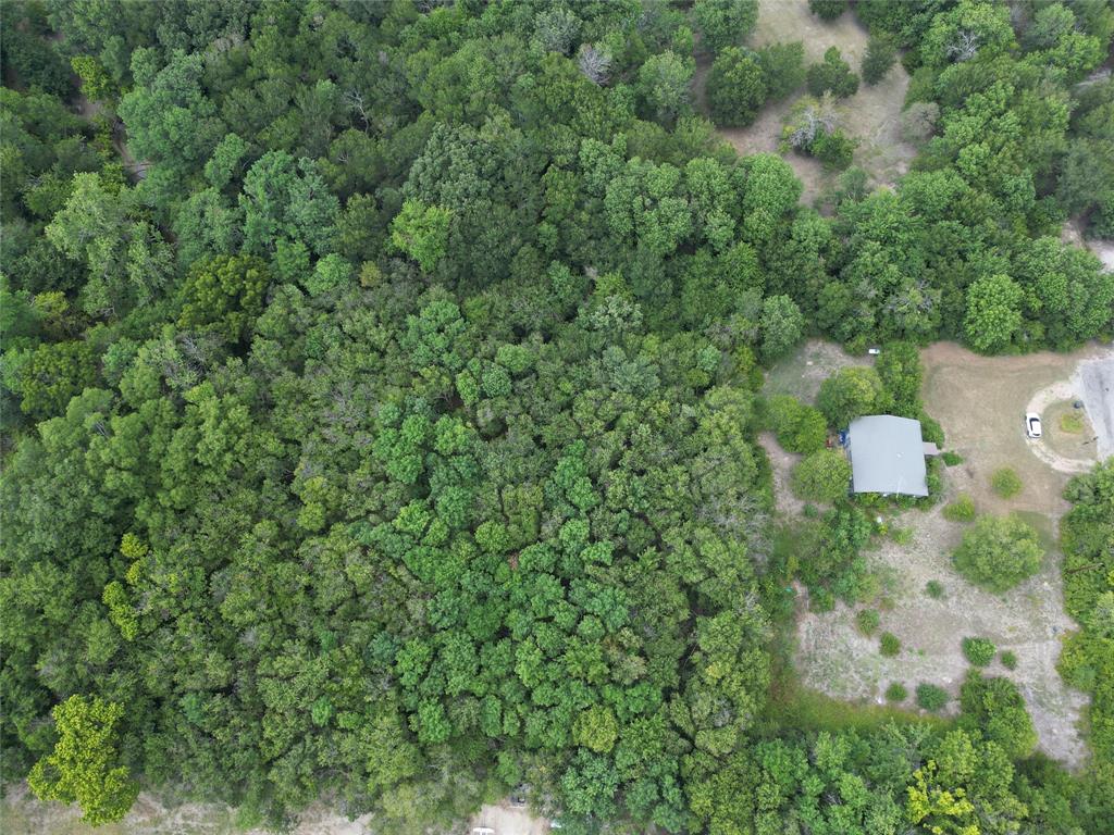 an aerial view of residential house with outdoor space and trees all around