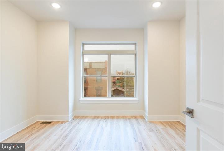 an empty room with wooden floor and windows