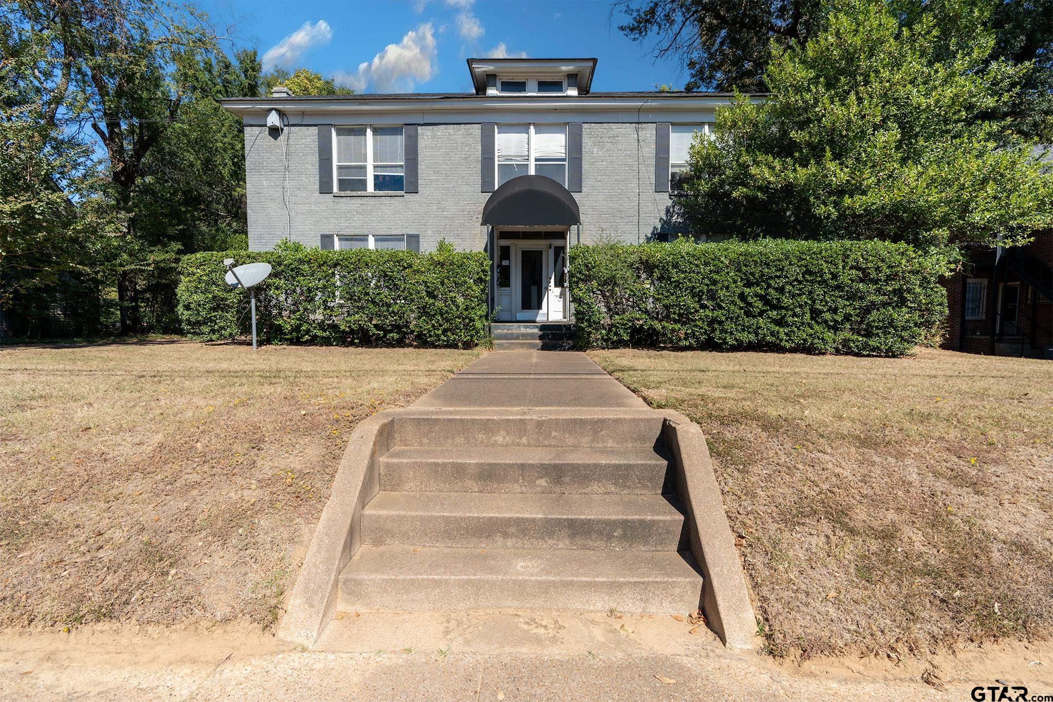 a front view of a house with plants and trees