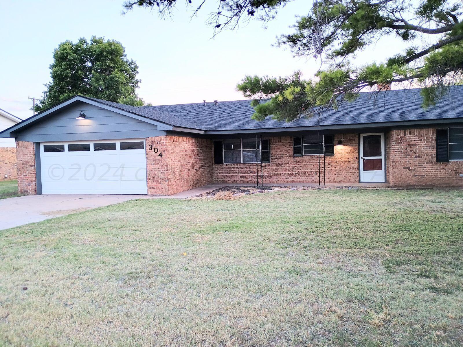 a front view of house with yard and trees in the background