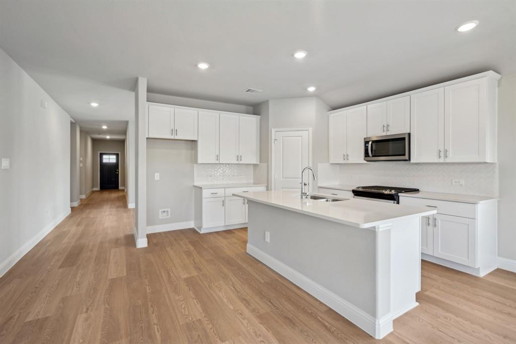 a kitchen with a sink a microwave a refrigerator and cabinets