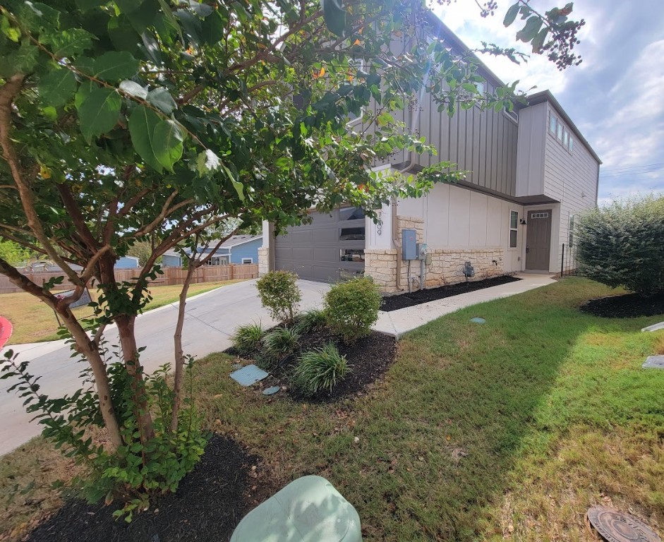 a backyard of a house with plants and large tree