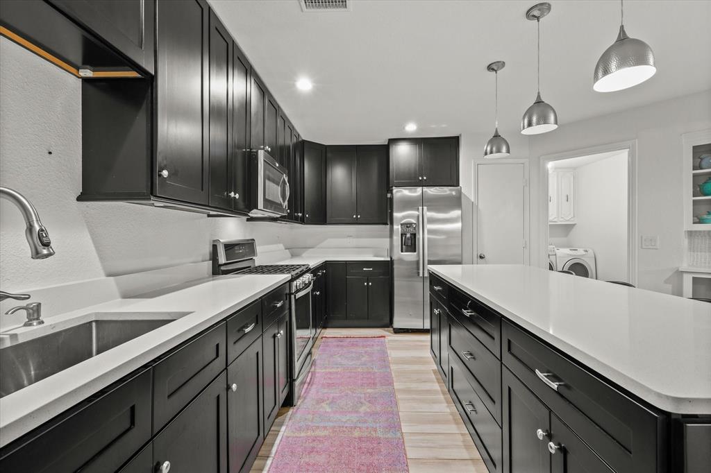 a kitchen with a sink stainless steel appliances a counter space cabinets and furniture