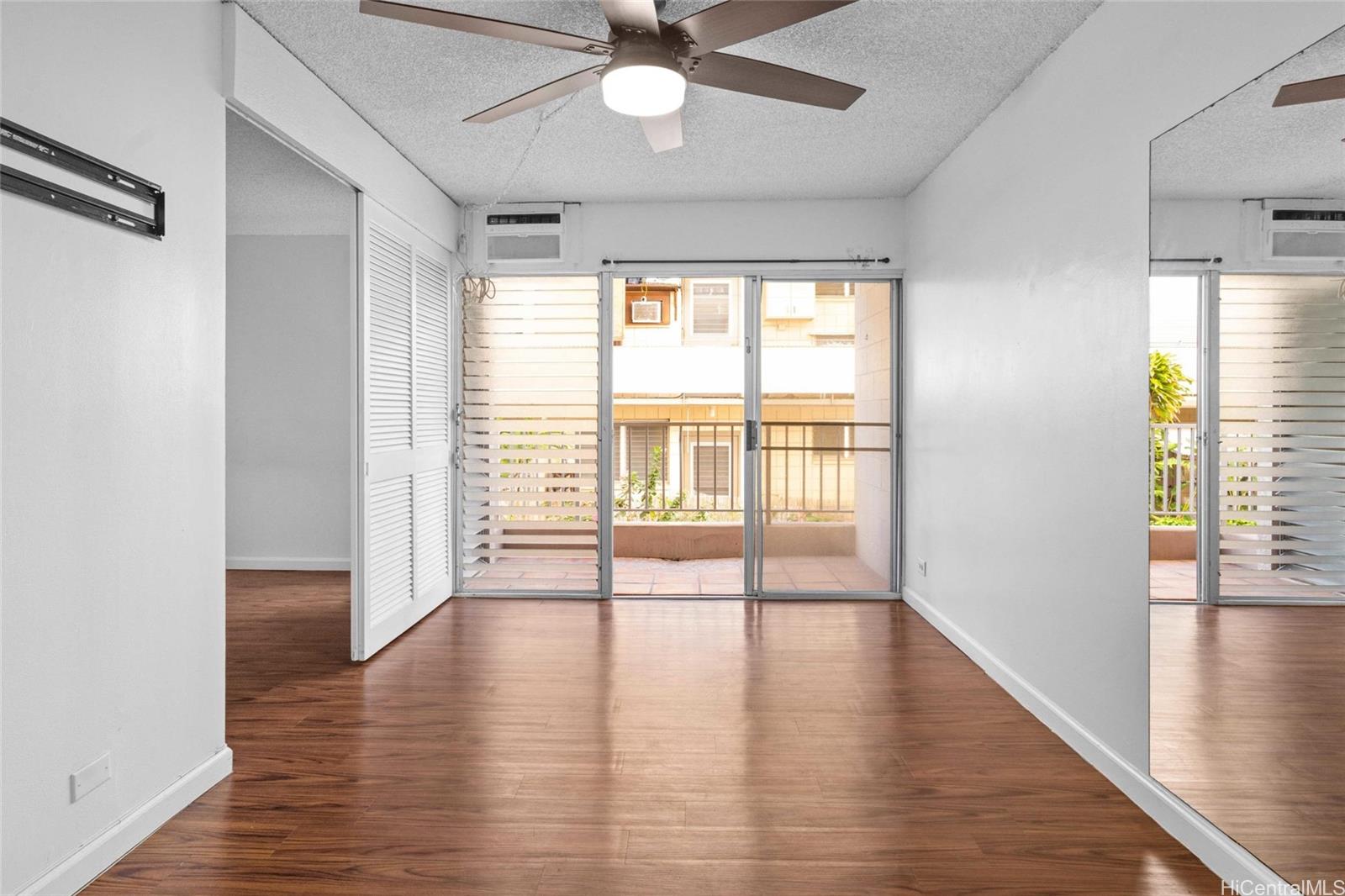 a view of an empty room with wooden floor and a window