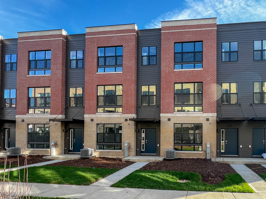 a front view of an apartment building with yard and outdoor seating