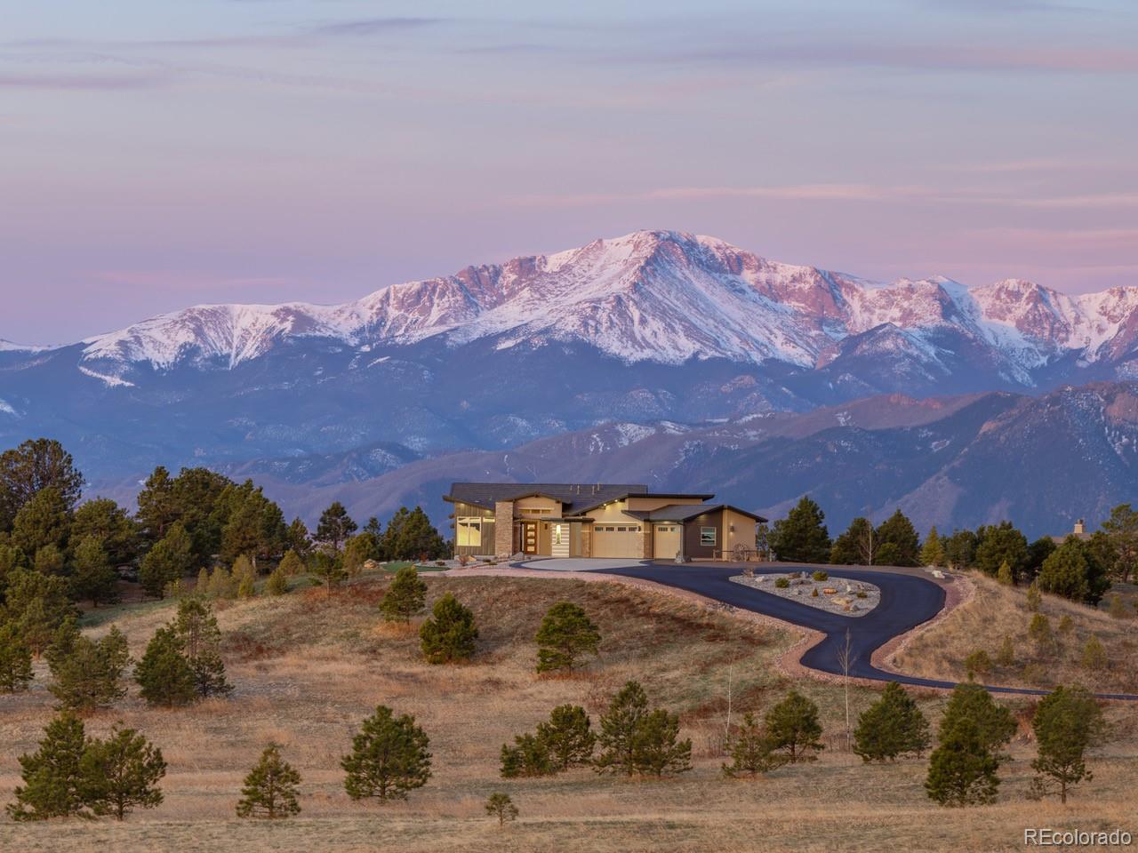 a front view of a house with a yard and mountain view in back