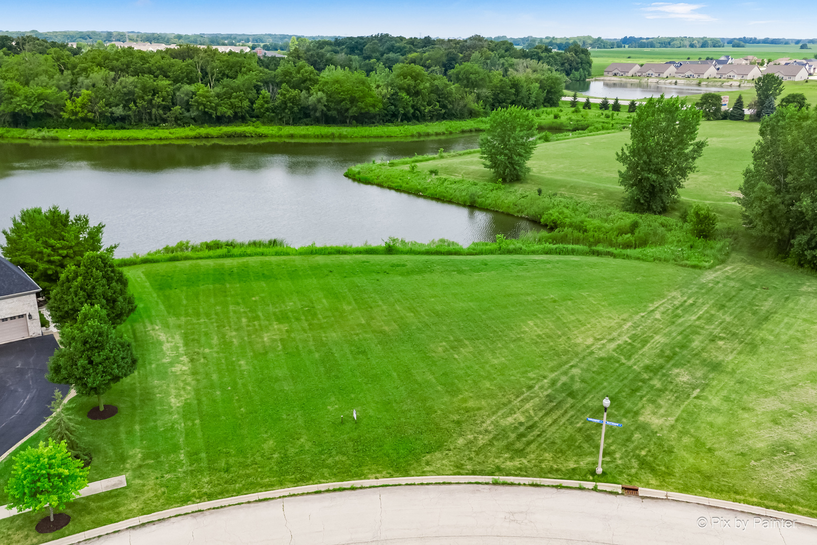 a view of a water pond with green yard