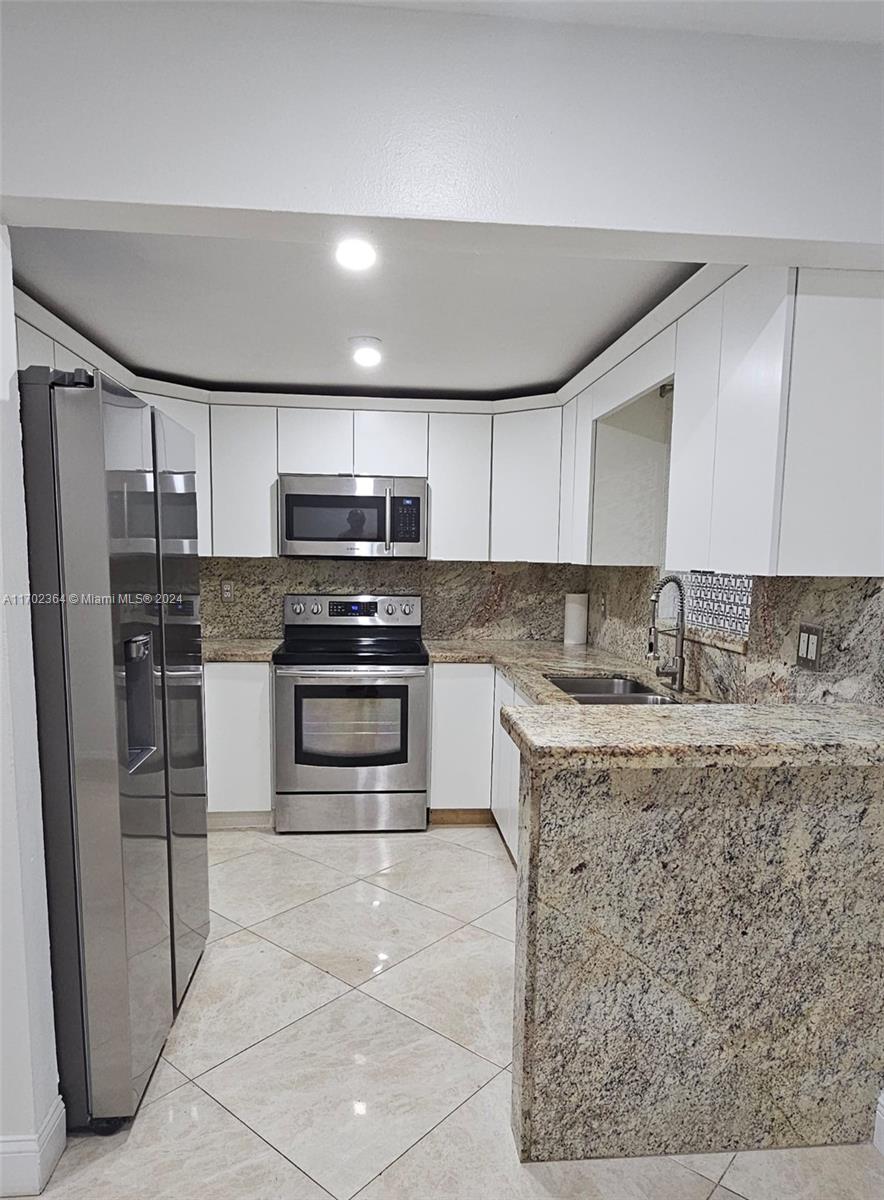 a kitchen with stainless steel appliances granite countertop a stove a sink and a refrigerator