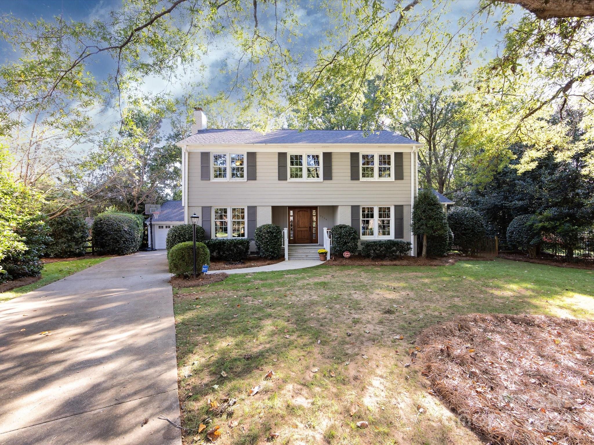 a front view of a house with a garden and trees