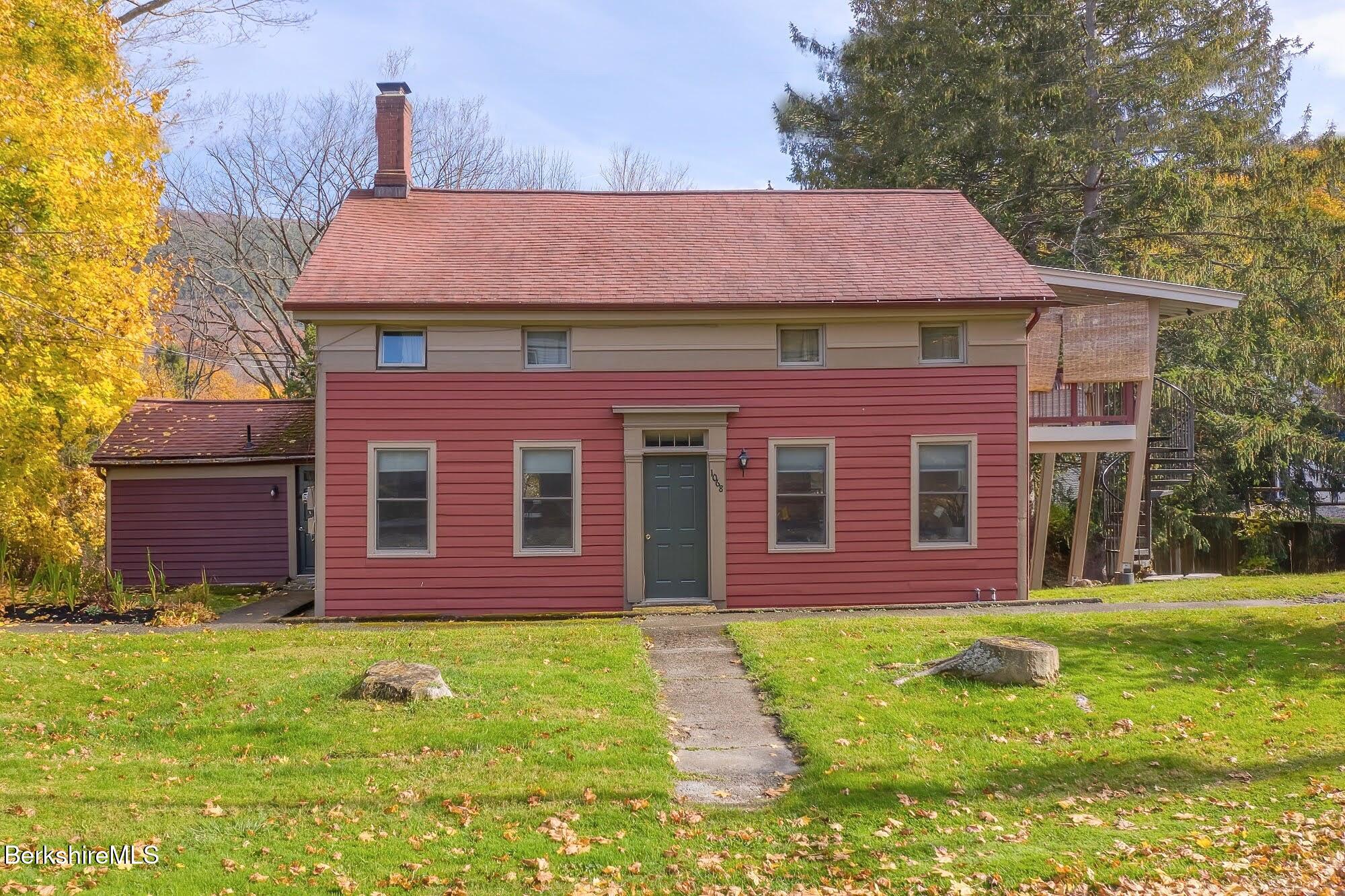 a view of a brick house with a yard potted plants and a large tree