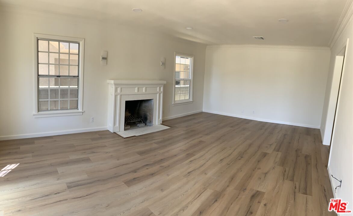 an empty room with wooden floor fireplace and windows