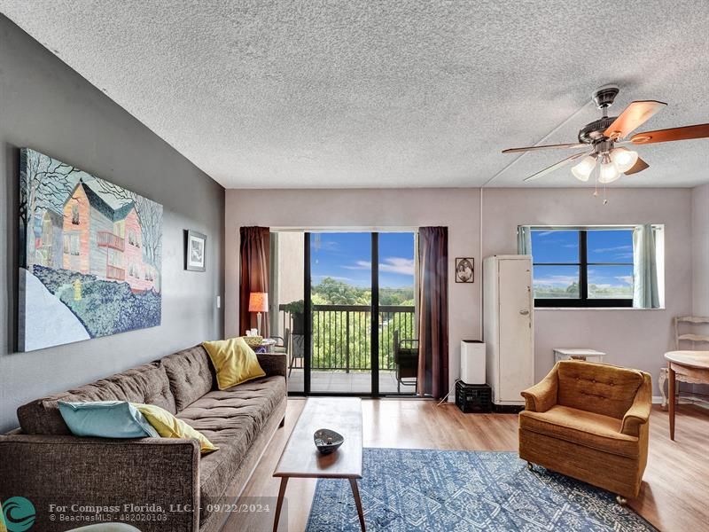 a living room with furniture two large window and a flat screen tv