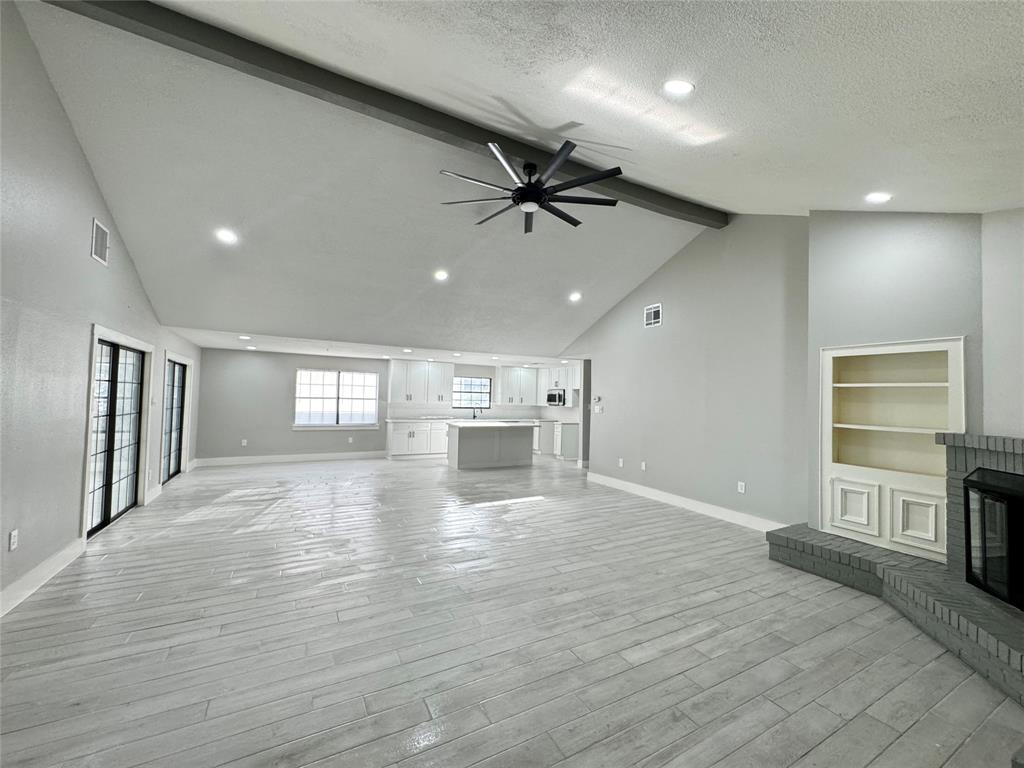 a view of an empty room with a window and wooden floor