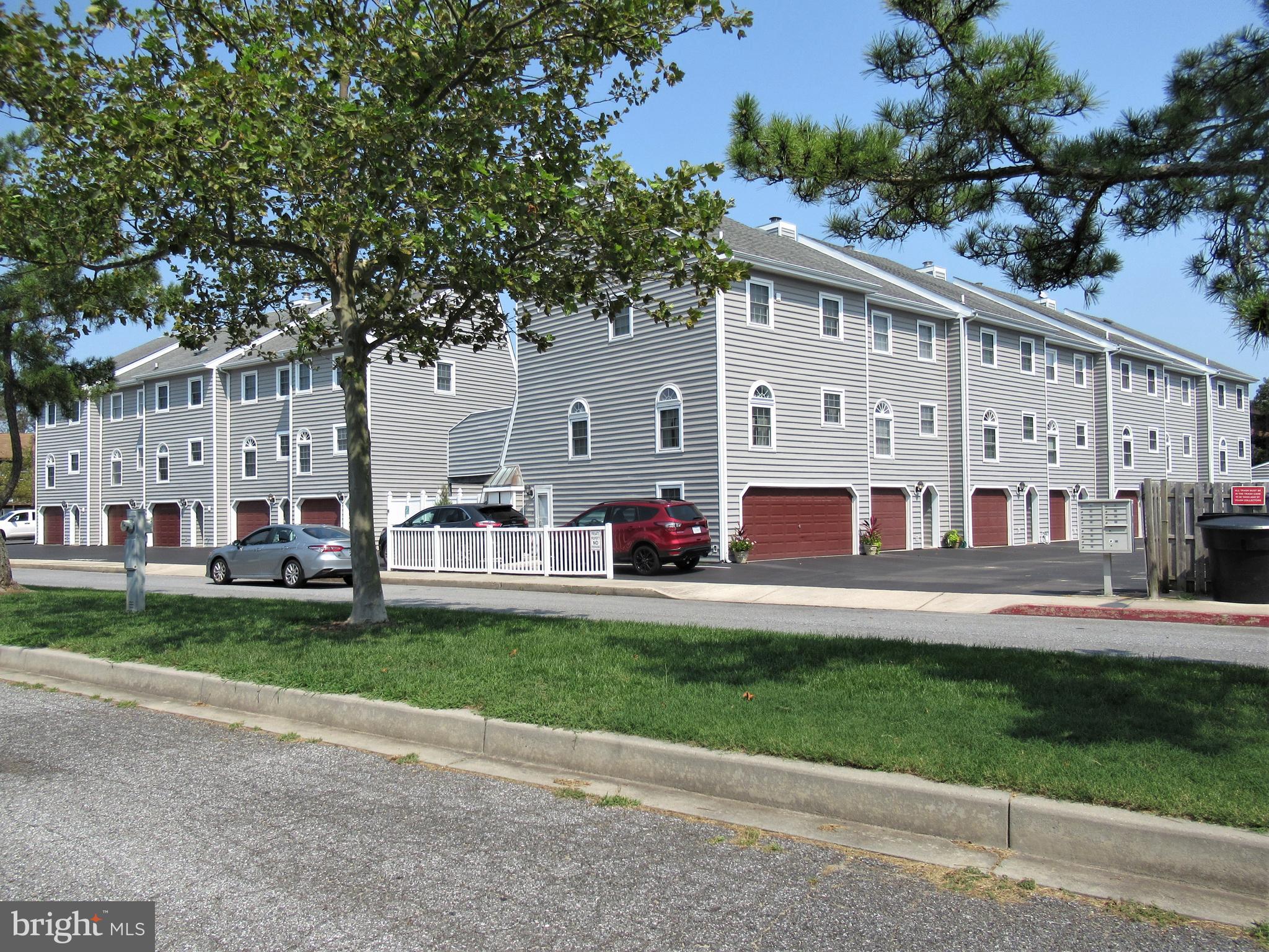 a view of a white house with a big yard and large trees