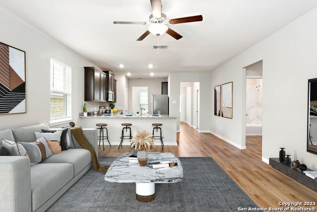 a living room with furniture kitchen view and a wooden floor