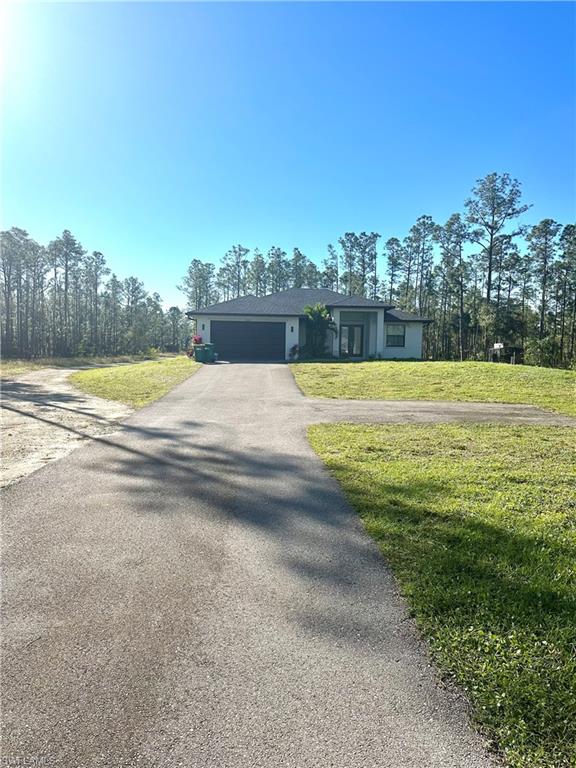 Single story home with a garage and a front yard