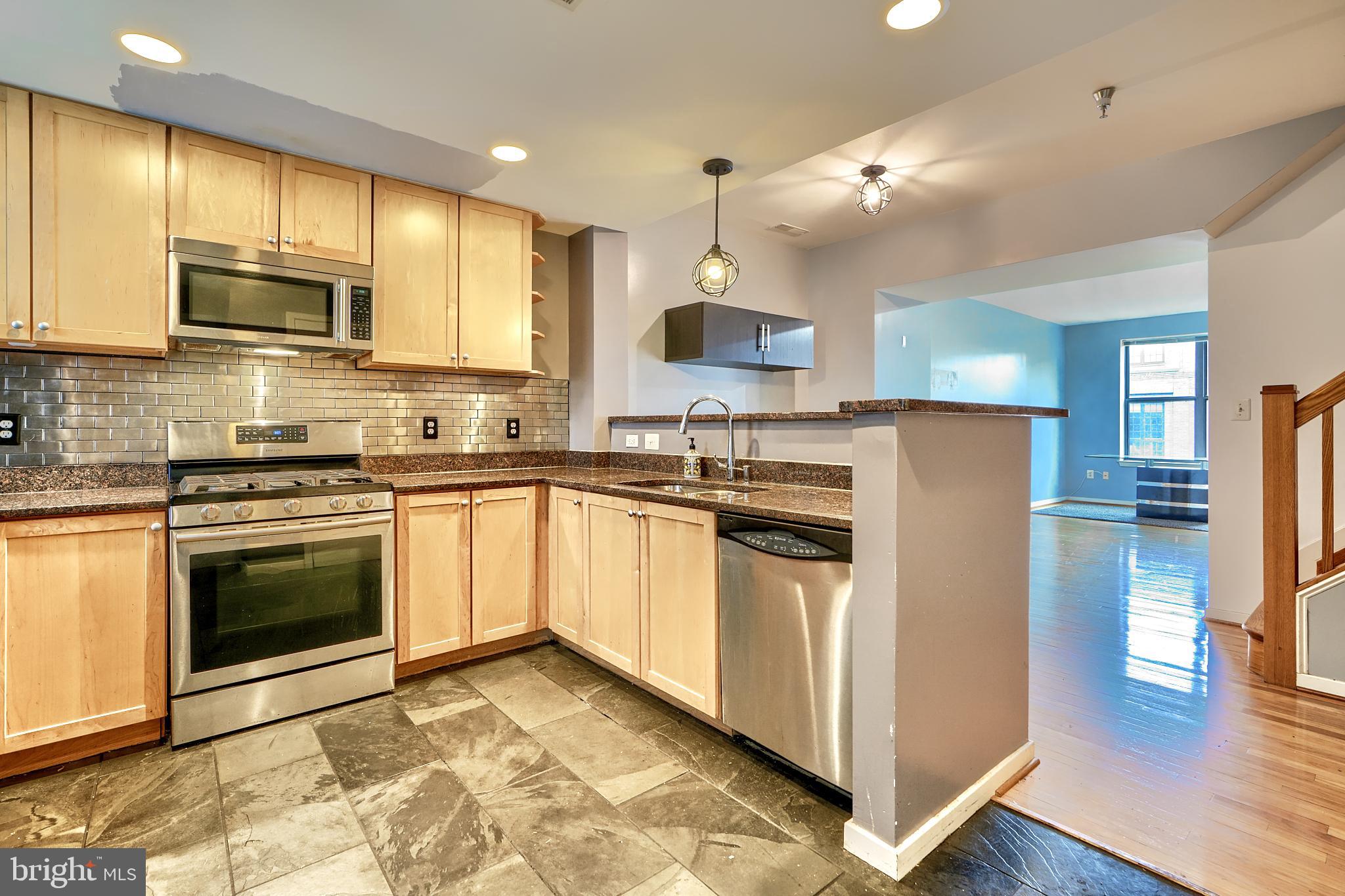 a kitchen with stainless steel appliances granite countertop a refrigerator sink and stove