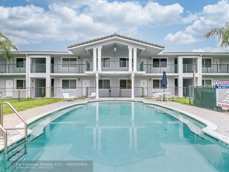 a view of a large pool with a lawn chairs and a yard