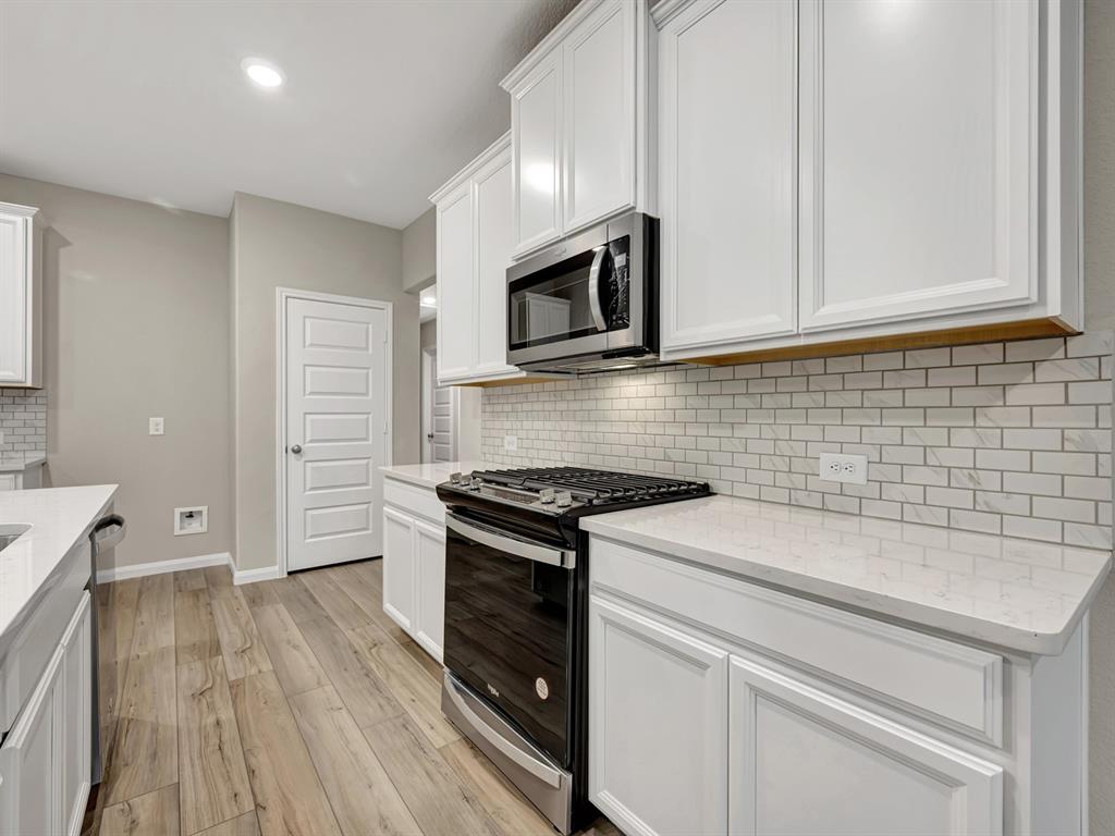 a kitchen with granite countertop cabinets stainless steel appliances and wooden floor