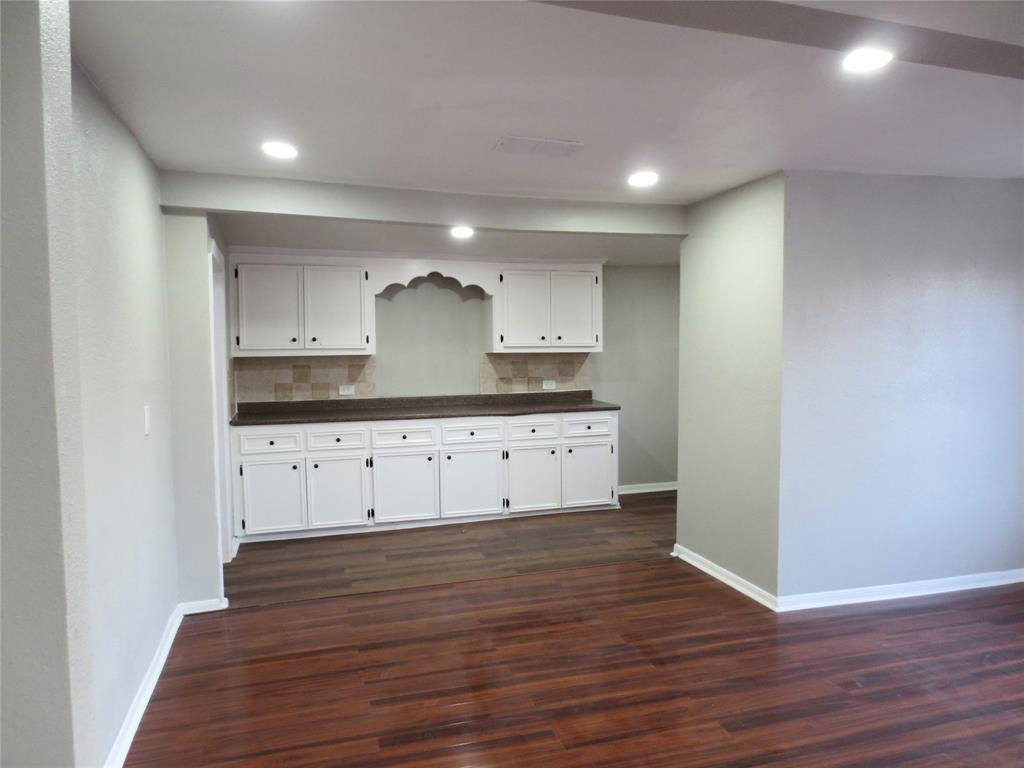 a kitchen with granite countertop white cabinets and wooden floors