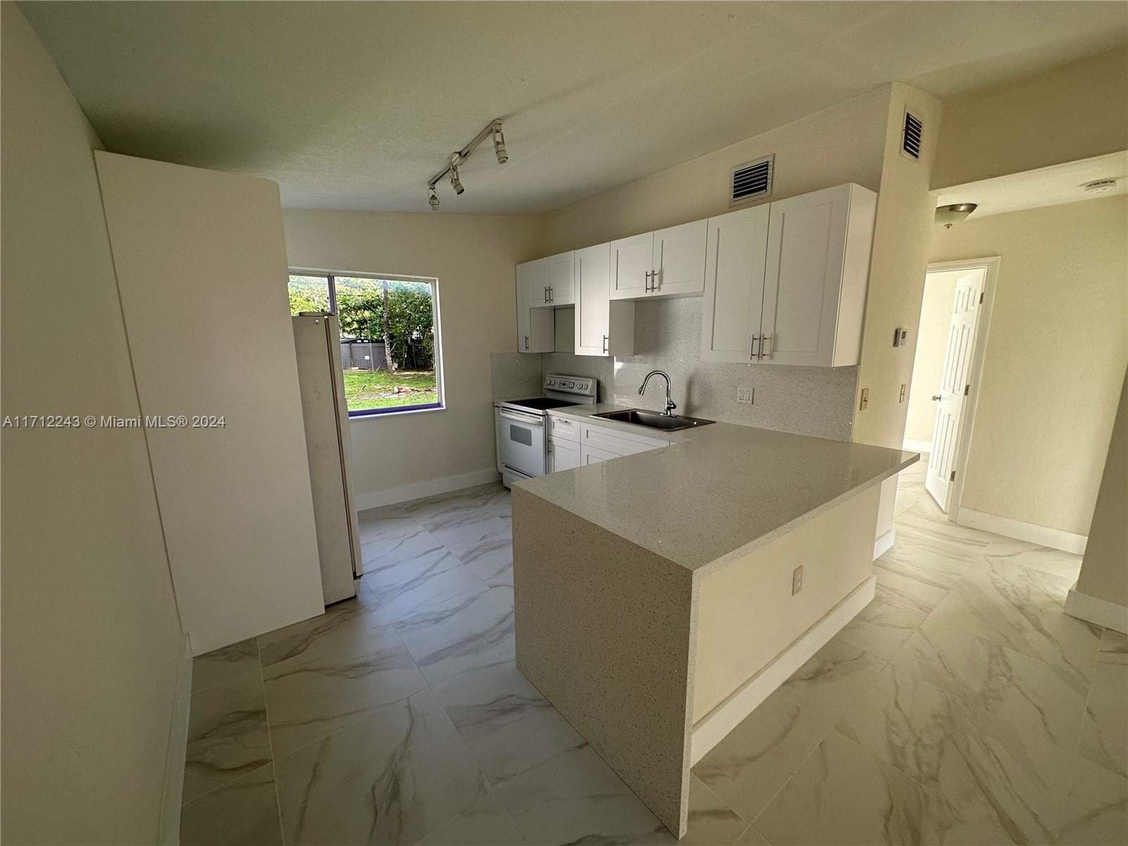 a view of a kitchen with wooden floor and electronic appliances