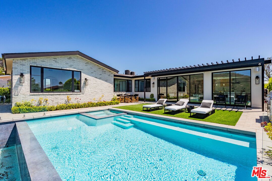 a view of swimming pool with outdoor seating and house in the background