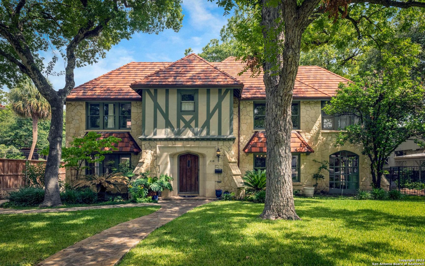 a front view of a house with a garden and trees