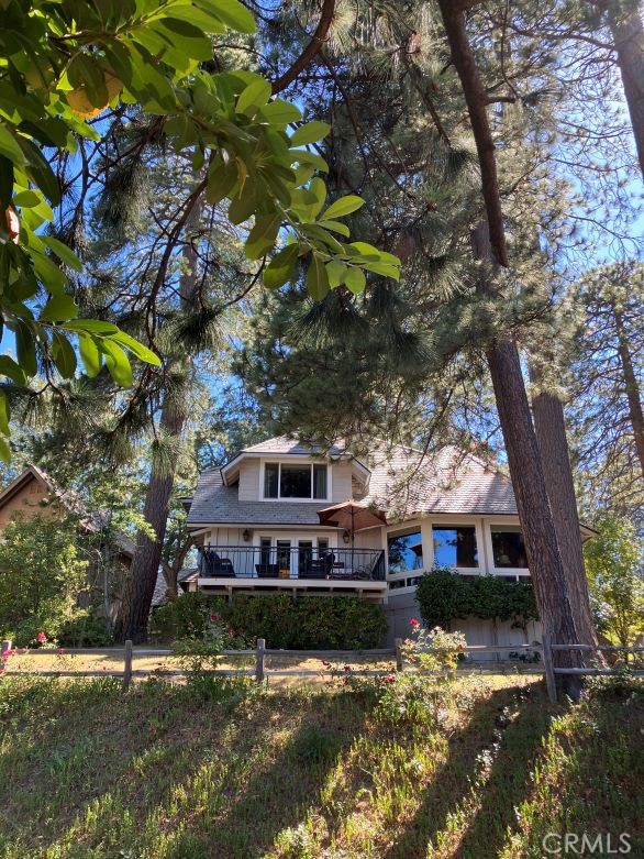 a view of a house with a yard and a large tree in the background