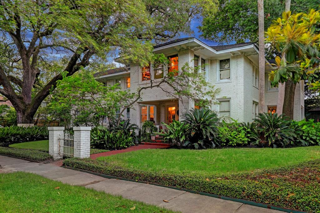 a front view of a house with a garden and trees