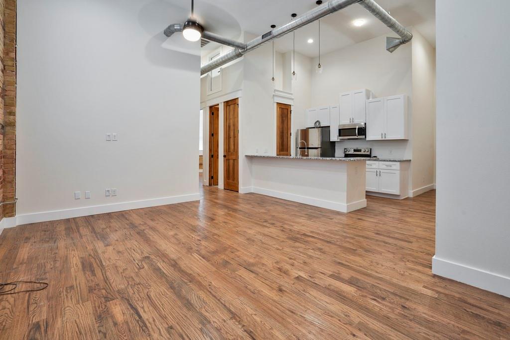 a view of a kitchen with a sink and dishwasher a refrigerator with wooden floor