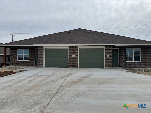 a front view of a brick house with a yard and garage