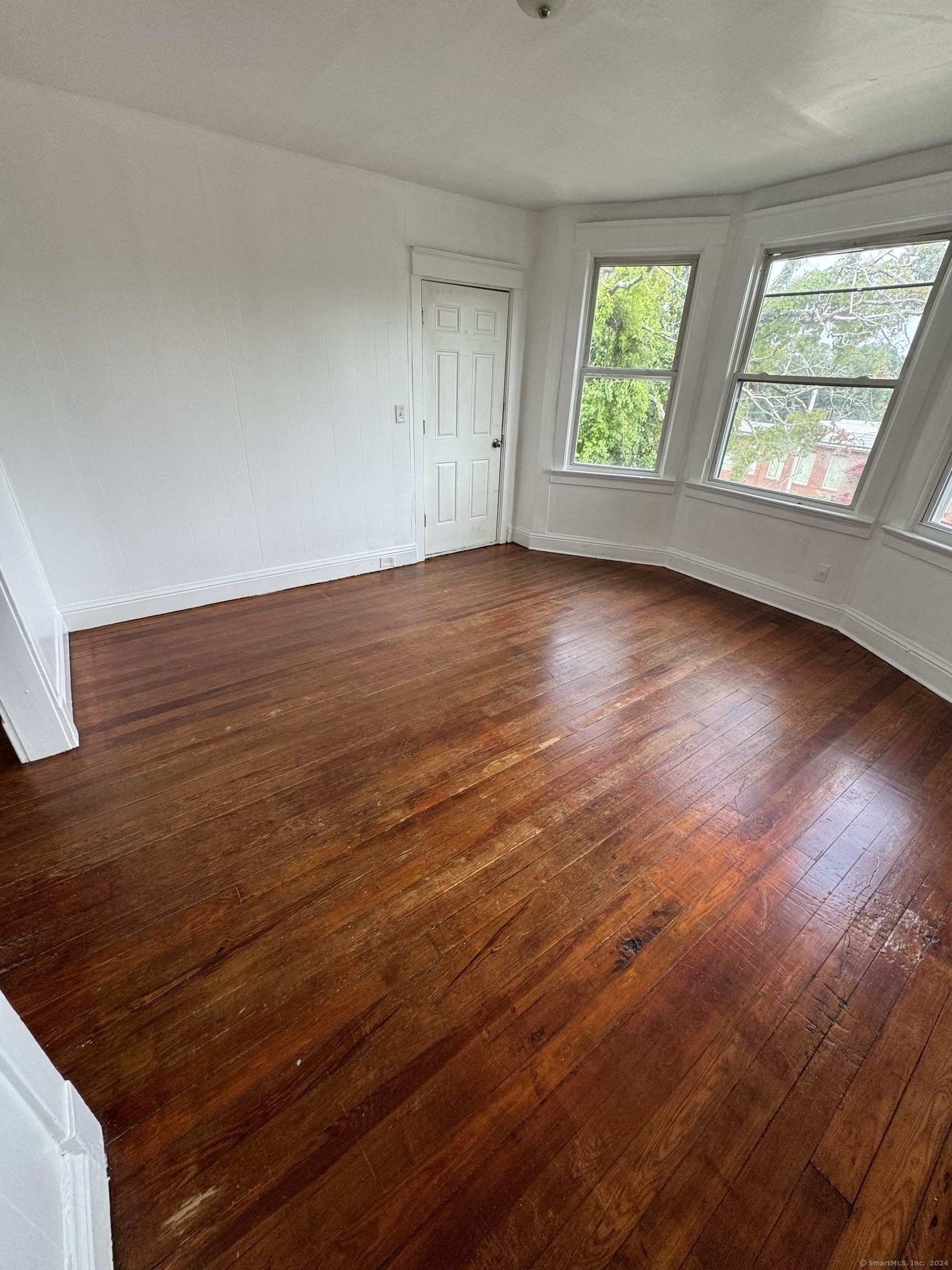 an empty room with wooden floor and windows