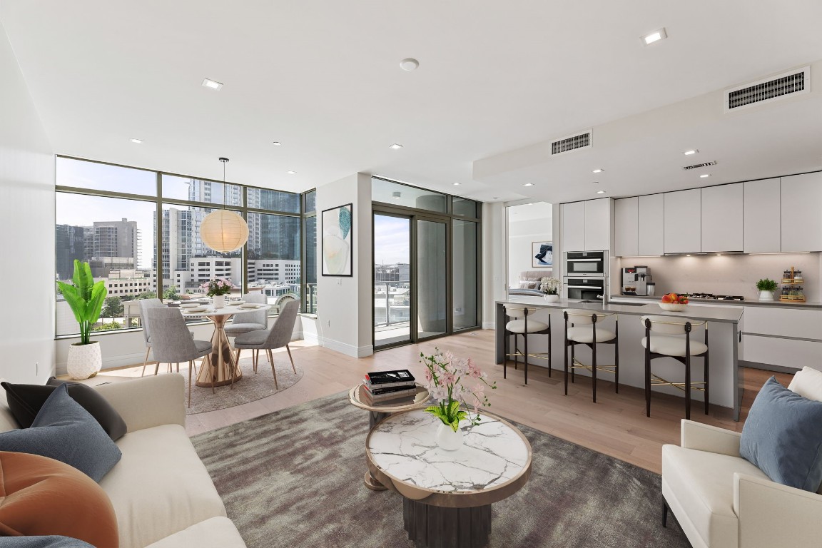 a living room with furniture kitchen view and a large window