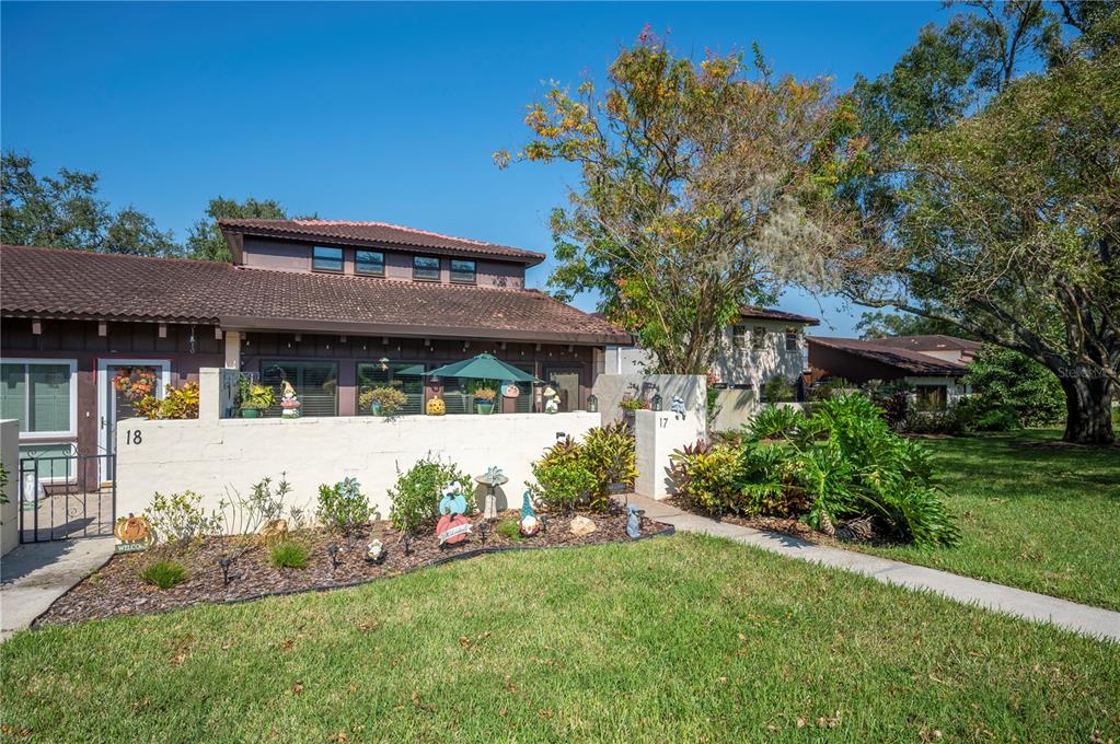 a view of a house with a yard potted plants and a large tree