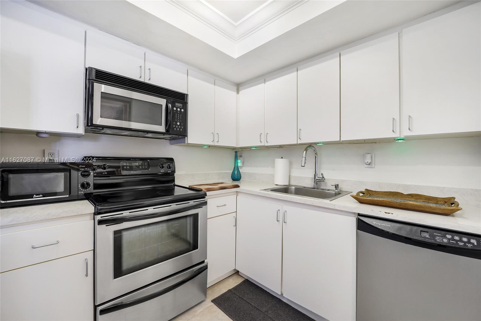 a kitchen with granite countertop white cabinets and stainless steel appliances