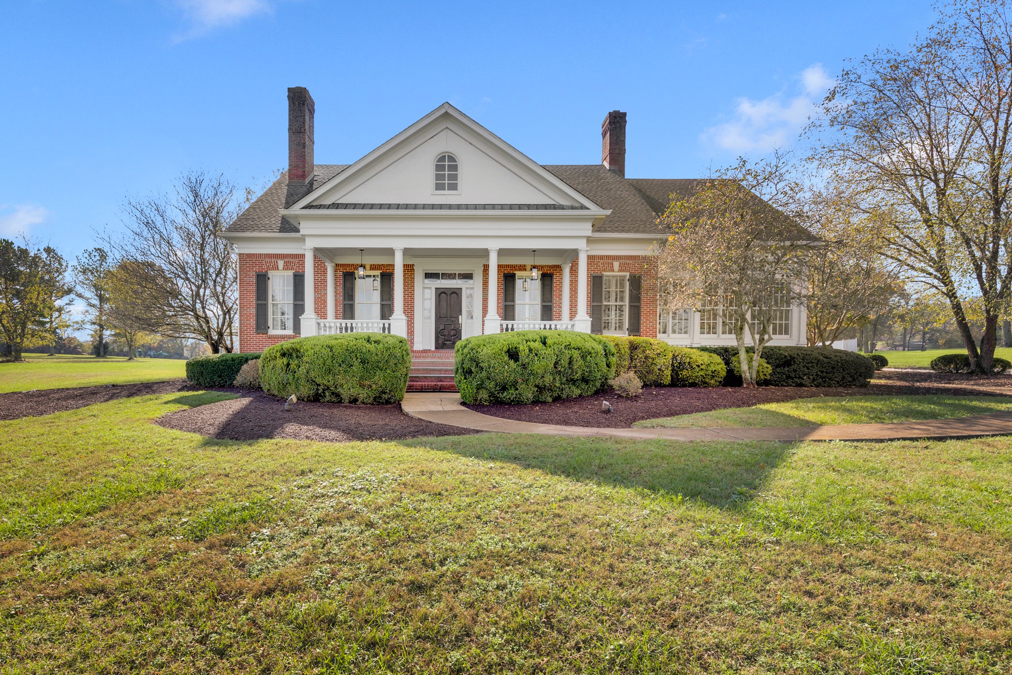 a front view of a house with garden and trees