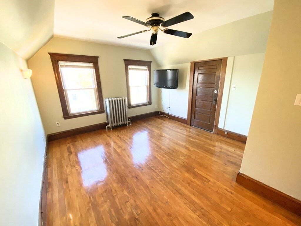 a view of empty room with wooden floor and fan