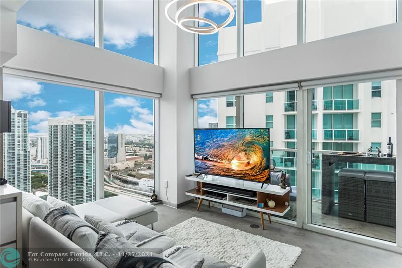 a living room with furniture a flat screen tv and floor to ceiling window