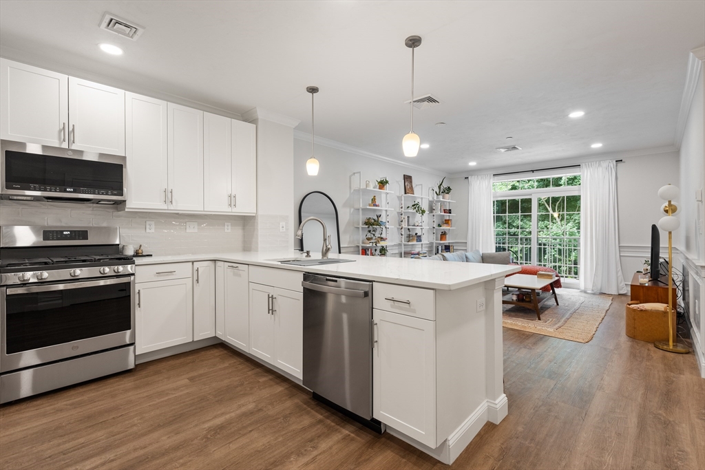 a kitchen with a sink stove and wooden floor